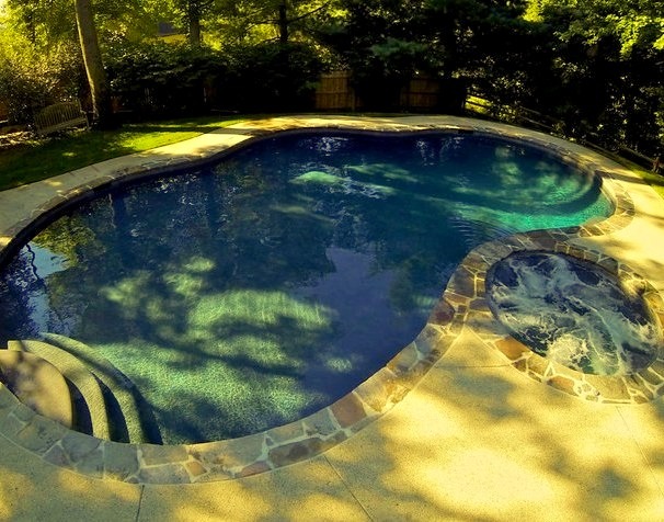 Mid-sized traditional backyard concrete and naturally-shaped hot tub design
